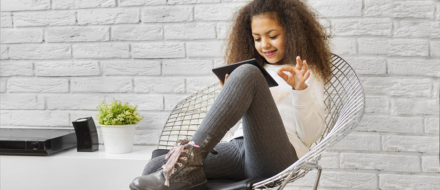  Girl sitting in chair on tablet learning how to be a digital leader. 